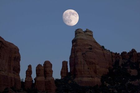 a nearly full moon rises over red rock spires near Sedona, Arizonaの写真素材