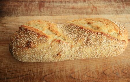 sesame seed bread isolated on wooden cutting boardの写真素材
