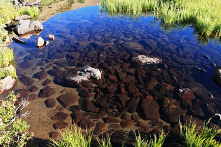 clear mountain pool with rocky bottomの写真素材