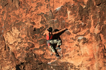 woman rock climber in red climbing a red sandstone cliff at Red Rocks, Nevadaの写真素材