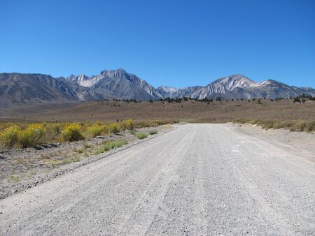 rural road extends towards distant mountains の写真素材