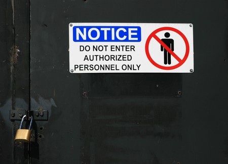 white notice do not enter authorized personnel only sign on a black padlocked doorの写真素材