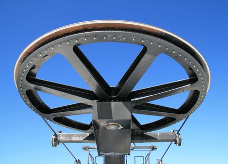 giant pulley wheel from the top of a ski lift with a blue sky backgroundの写真素材