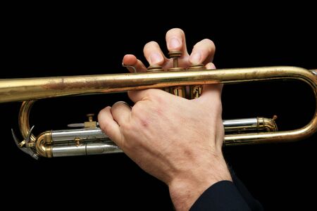 detail of a man's hands playing a trumpet with dark backgroundの写真素材