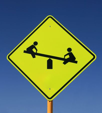 playground road sign with see saw in yellow and black on blue sky backgroundの写真素材
