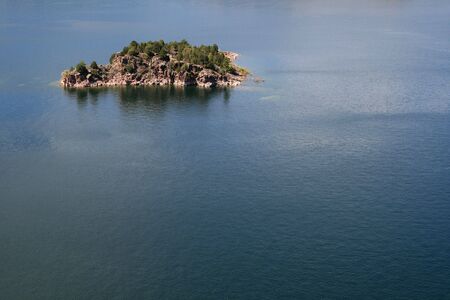small rocky island surrounded by blue water with copy spaceの写真素材