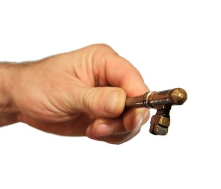 an isolated man's hand holds an antique brass key towards the viewer with selective focus on the key の写真素材