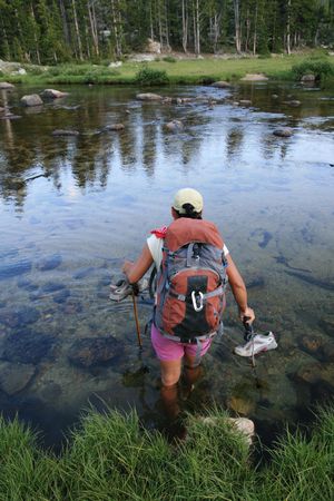 woman backpacker wading across the Popo Agie River in Wyoming's Wind River Rangeの写真素材