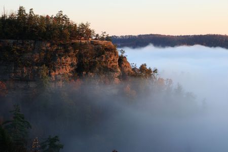 a sandstone cliff rises above early morning fog in the autumnの写真素材
