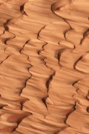 vertical image of reddish sand and mud ripples caused by flowing waterの写真素材