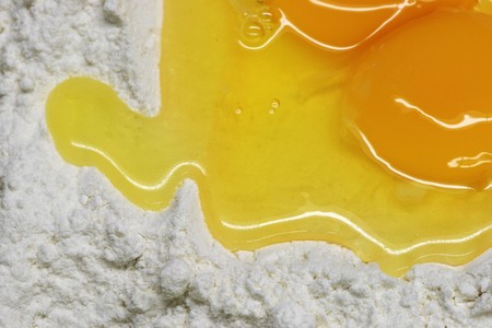 close up of broken eggs and white flour for making pastaの写真素材