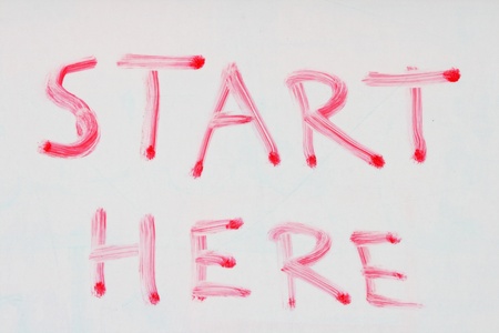 start here written in red dry erase marker on a used white boardの写真素材