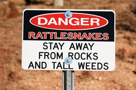 red white and black danger rattlesnakes sign on a postの写真素材