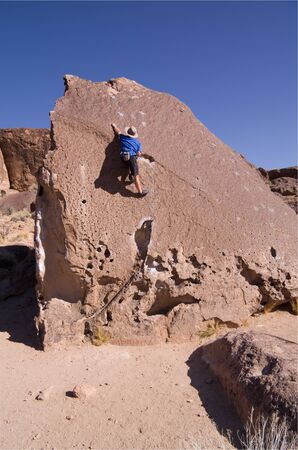 a man rock climbing a tall boulderの写真素材