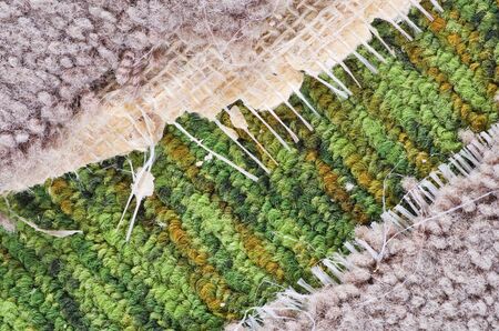 background detail of old ripped tan carpet over green carpetの写真素材