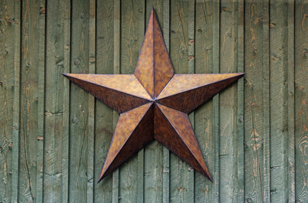 metal five pointed star on a rough wood wallの写真素材