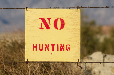 wood no hunting sign wired to a barbed wire fenceの写真素材