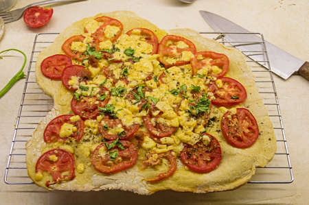 rough homemade pizza cooling on a rack on a messy counterの写真素材