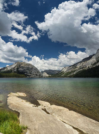 Tenaya Lake in the Yosemite National Park high country with foreground rock slab and white clouds in the skyの写真素材