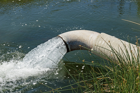 groundwater pumping out of a pipe into an irrigation canal in Californiaの写真素材