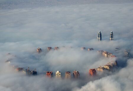 tall buildings rise above ground fog as viewed from above in Doha, Qatarの写真素材