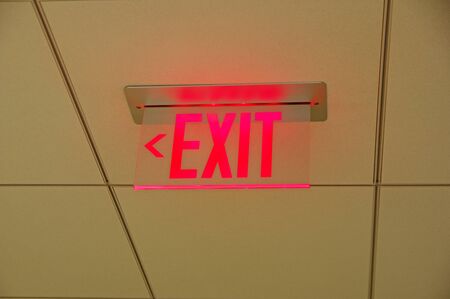 red glowing exit sign on a drop ceilingの写真素材