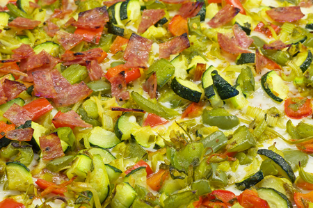 angled background view of a pizza top with vegetables and salamiの写真素材