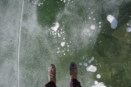 view down while ice skating on a lake showing the end of a man's legs and ice skatesの写真素材