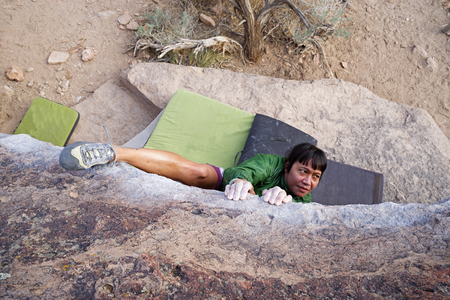 a woman bouldering on a traverse from above with a heel hookの写真素材
