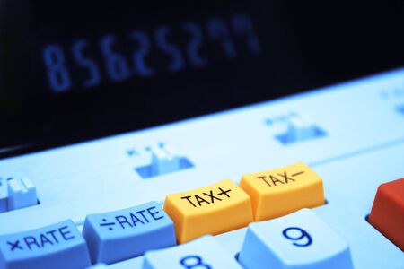 Calculator showing tax plus button in focus with numbers in the out of focus backgrounndの写真素材