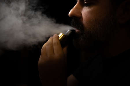 Profile view of a bearded mature man vaping against the light.の写真素材
