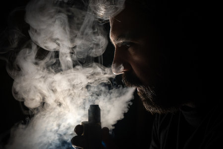 Profile view of a bearded mature man vaping against the light.の写真素材
