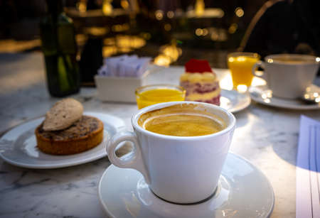 Close-up of cup of coffee with cinnamon dessert behind.の写真素材