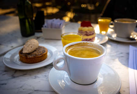 Close-up of cup of coffee with cinnamon dessert behind served at breakfast.の写真素材