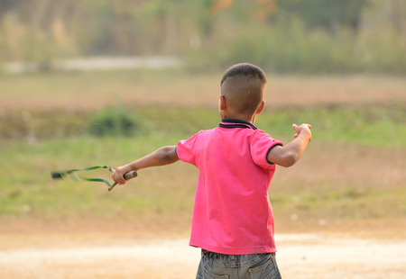Funny kid shooting wooden slingshotの写真素材