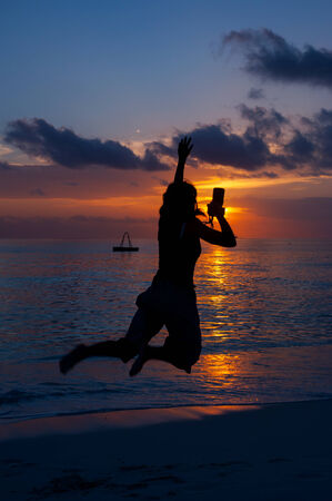 the silhouette of woman, who jumps on a beachの写真素材