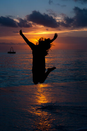 the silhouette of woman, who jumps on a beachの写真素材