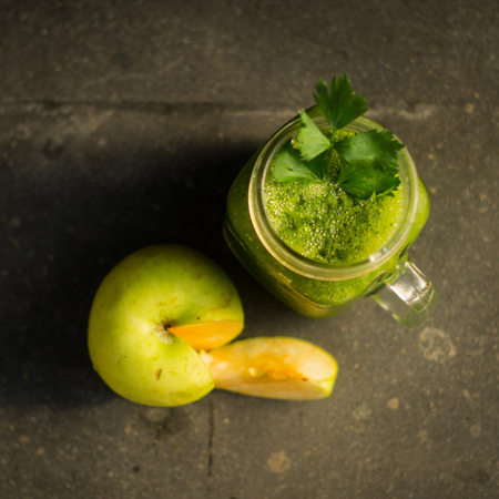 Healthy detox green apple and vegetables juice in Mason jar with celery on the top. It serves on black natural stoneの写真素材