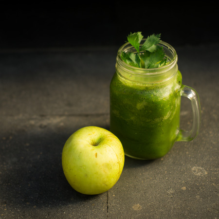 Healthy detox green apple and vegetables juice in Mason jar with celery on the top. It serves on black natural stoneの写真素材