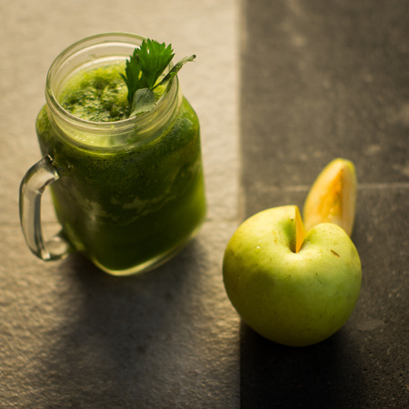 Healthy detox green apple and vegetables juice in Mason jar with celery on the top. It serves on black natural stoneの写真素材