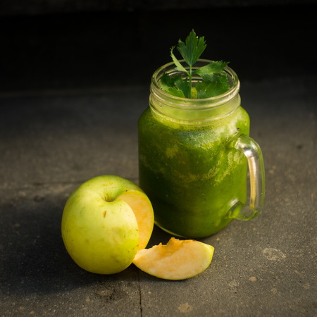 Healthy detox green apple and vegetables juice in Mason jar with celery on the top. It serves on black natural stoneの写真素材