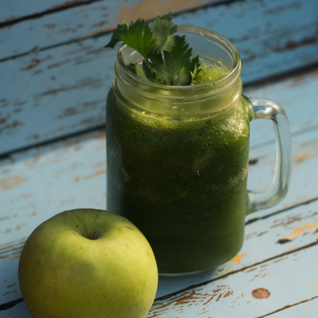 Healthy detox green apple and vegetables juice in Mason jar with celery on the top. It serves on wooden blue vintage backgroundの写真素材
