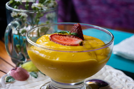 Boosting your day with fresh organic mango juice with mint leaf on top. It serves on the wood circular tableの写真素材