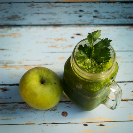 Healthy detox green apple and vegetables juice in Mason jar with celery on the top. It serves on wooden blue vintage backgroundの写真素材