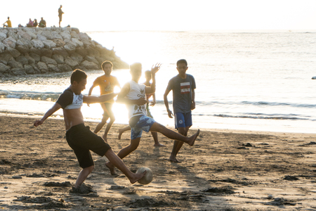 BADUNG,BALI/INDONESIA-APRIL 02 2019: Asian Teenager play football or soccer at the beach with sunset or golden hours backgroundのeditorial素材
