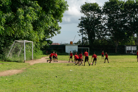 BADUNG,BALI/INDONESIA-APRIL 05 2019: Elementary student in Bali play football or soccer on the field with red jersey.のeditorial素材