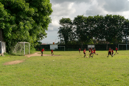 BADUNG,BALI/INDONESIA-APRIL 05 2019: Elementary student in Bali play football or soccer on the field with red jersey.のeditorial素材