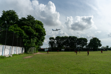 BADUNG,BALI/INDONESIA-APRIL 05 2019: Elementary student in Bali play football or soccer on the field near the airport with red jersey.のeditorial素材