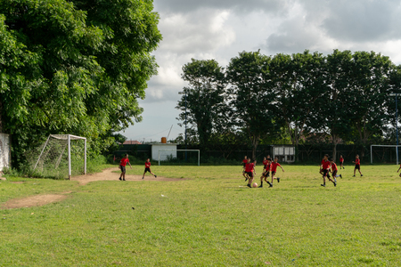 BADUNG,BALI/INDONESIA-APRIL 05 2019: Elementary student in Bali play football or soccer on the field with red jersey.のeditorial素材