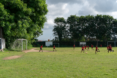 BADUNG,BALI/INDONESIA-APRIL 05 2019: Elementary student in Bali play football or soccer on the field with red jersey.のeditorial素材